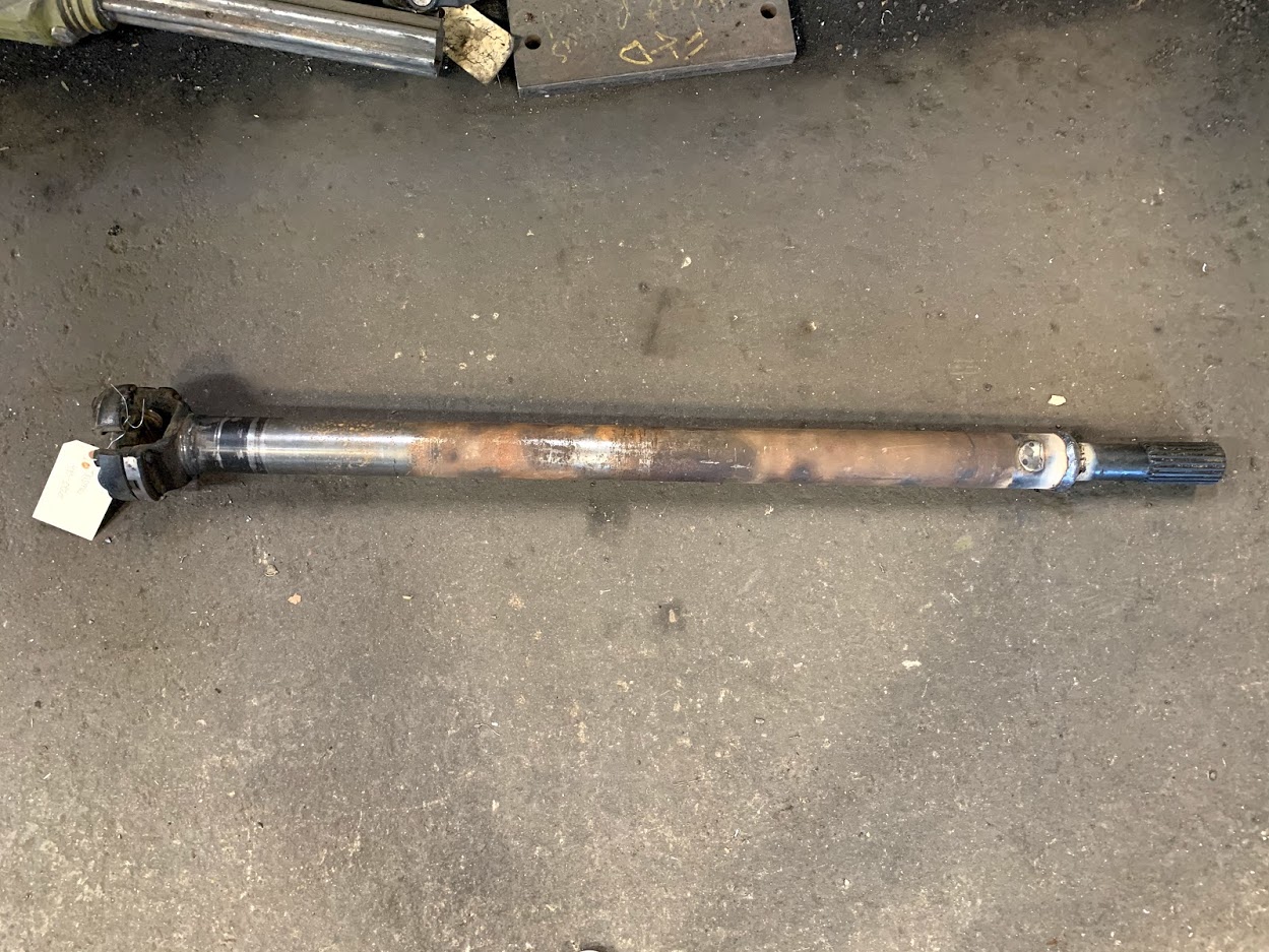 Custom-rebuilt driveline and axle shaft with U-joint at Riggs Machine & Welding shop in Stephenville, TX — tagged and ready for pickup