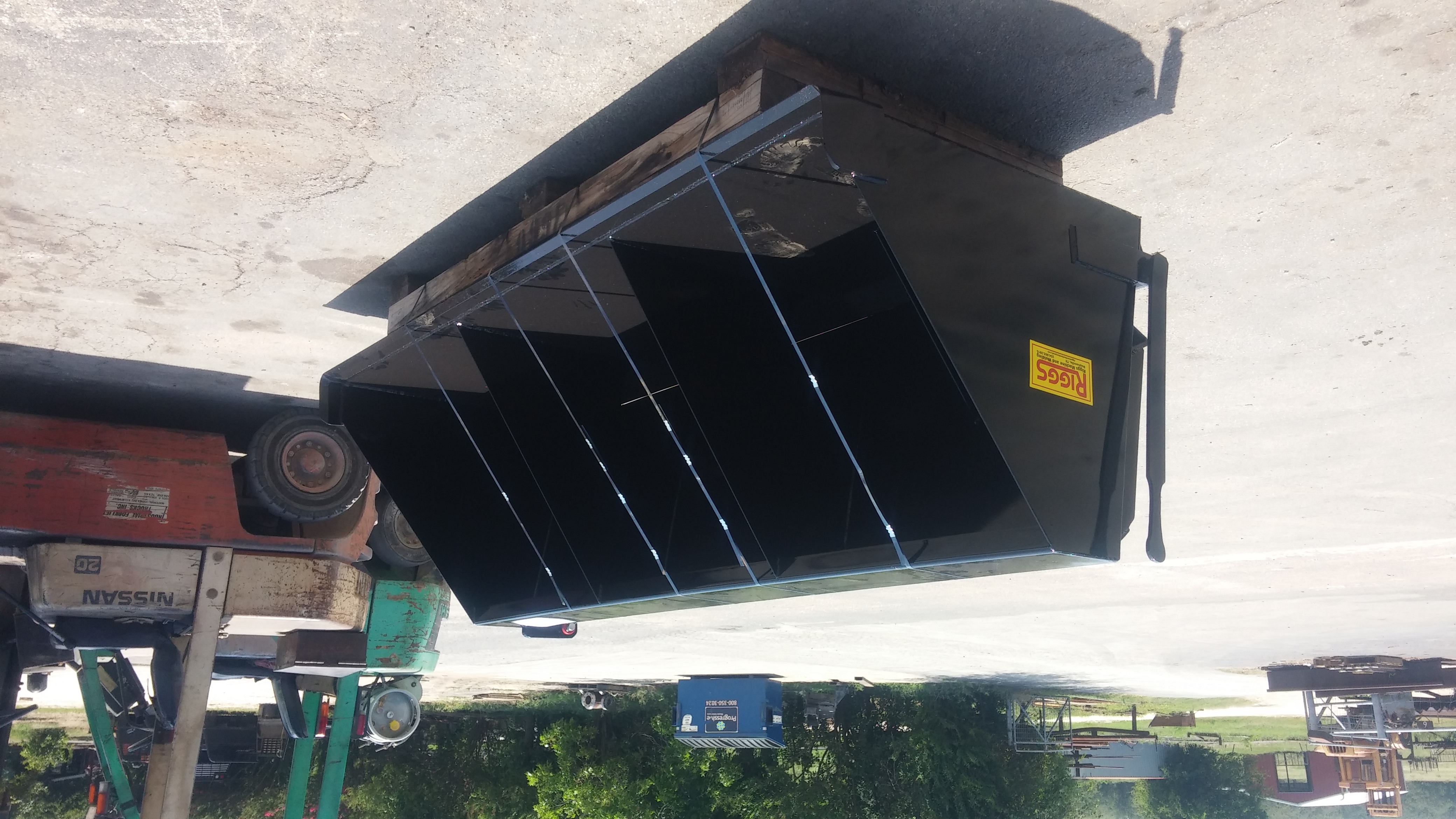 Black skid steer chip spreader bucket with Riggs Machine & Welding tag, fabricated and ready for pickup in Stephenville, TX