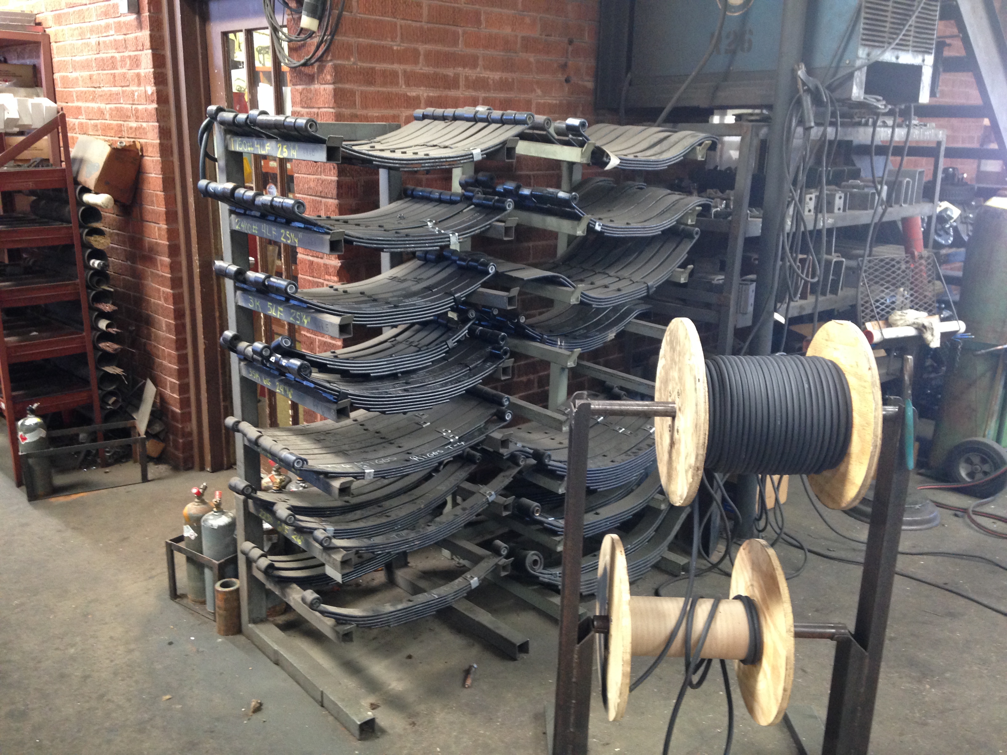 Labeled trailer leaf spring rack at Riggs Machine & Welding in Stephenville, TX — multiple sizes from 1600 lb to 3500 lb and heavier in stock